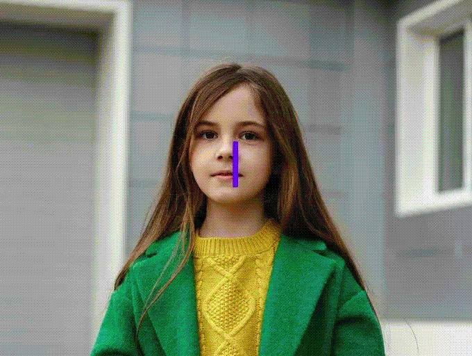Young girl with long brown hair wearing a yellow top and green coat looks forward.